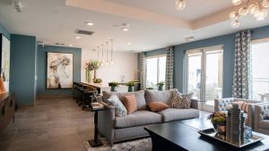 Living room with blue walls with a grey couch and large windows