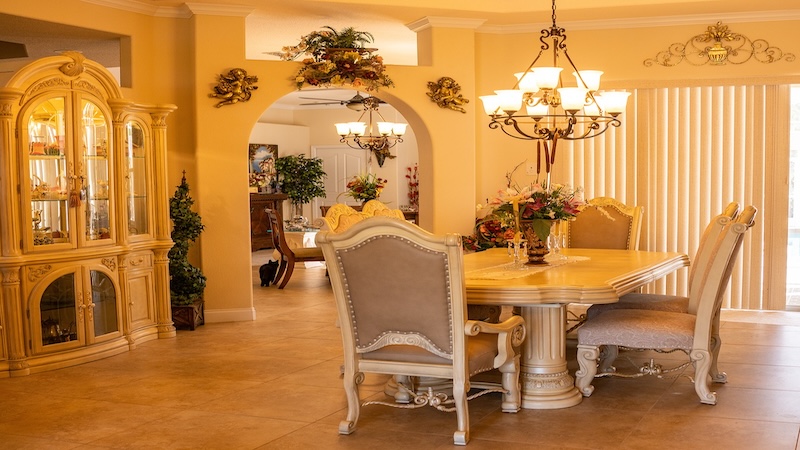 Dining room with a white table and beige chairs underneath a modern chandelier