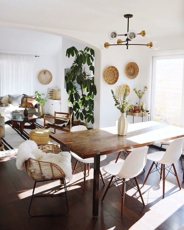 Dining room with wood dining table and 4 beige chairs with decor and a floor plant beside