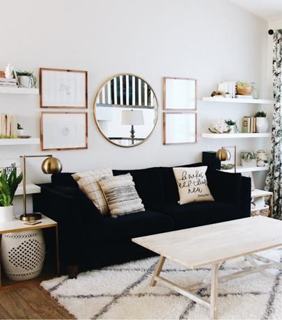 Living room with a black couch and decorative mirror and pictures on the wall above