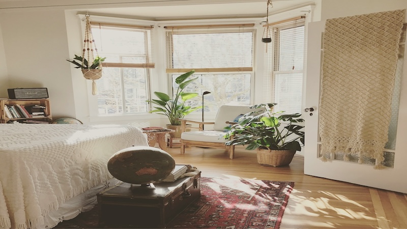 Bedroom with hanging plants, decorative chair, and a rug on the floor