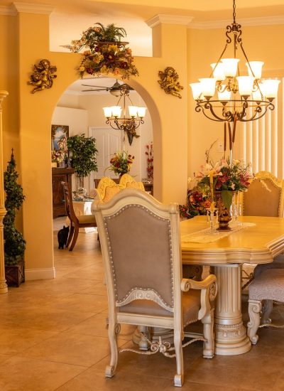 Dining room with a white table and beige chairs underneath a modern chandelier